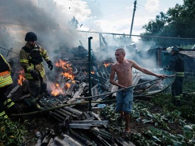 Житель Бахмута помогает пожарным тушить огонь во дворе жилого дома после обстрела. Фото: Igor Tkachev / AFP / Scanpix / LETA