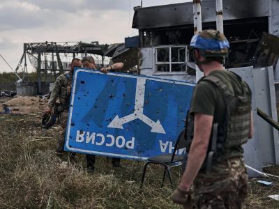 Украинские военные держат в руках дорожный знак-развилку Украина-Россия. Курская область России. Фото: Kostiantyn Liberov / Libkos / Getty Images